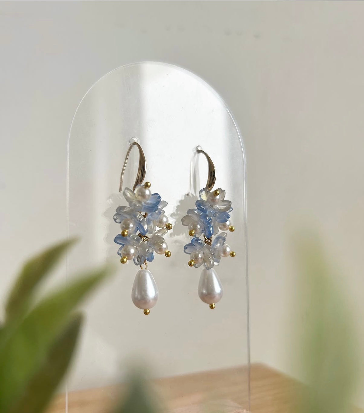 Pair of earrings with floral design and pearl-like elements on a white background