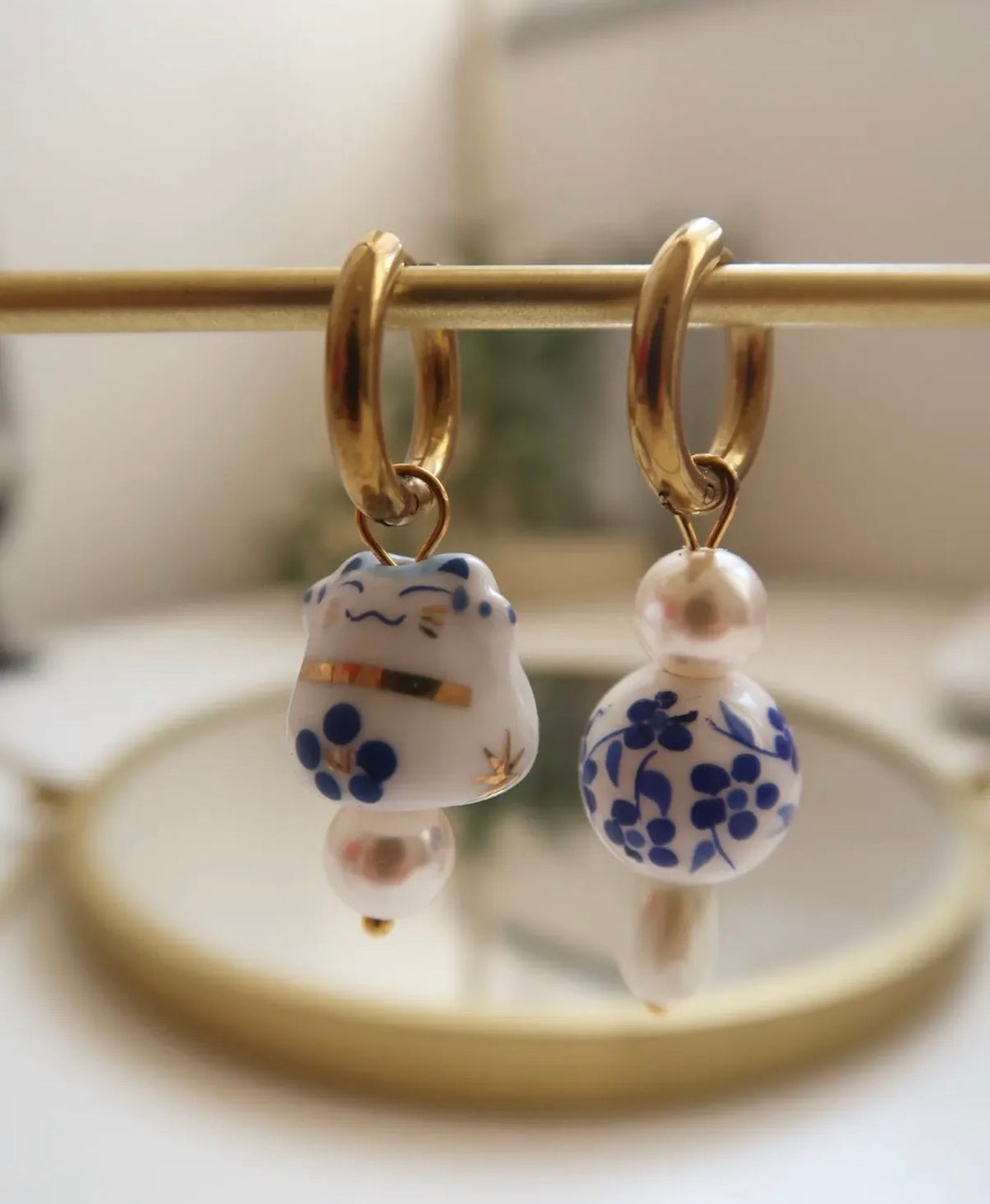 Pair of earrings with floral designs on a gold stick against a blurred background