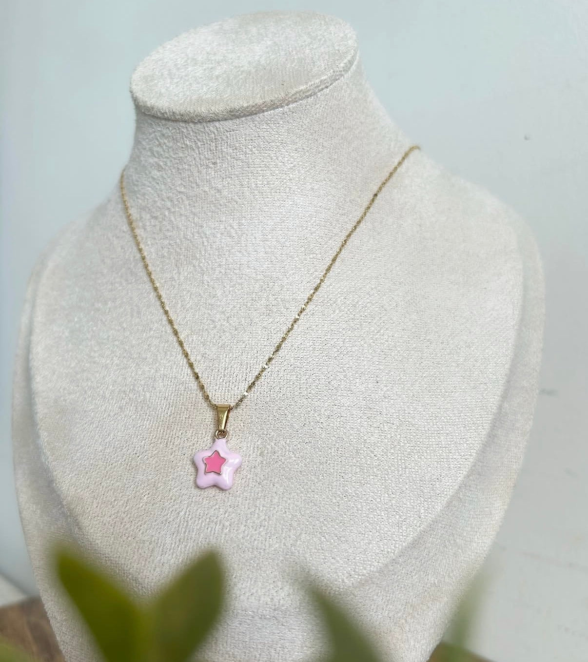 Necklace with a pink star-shaped pendant on a mannequin bust against a light background